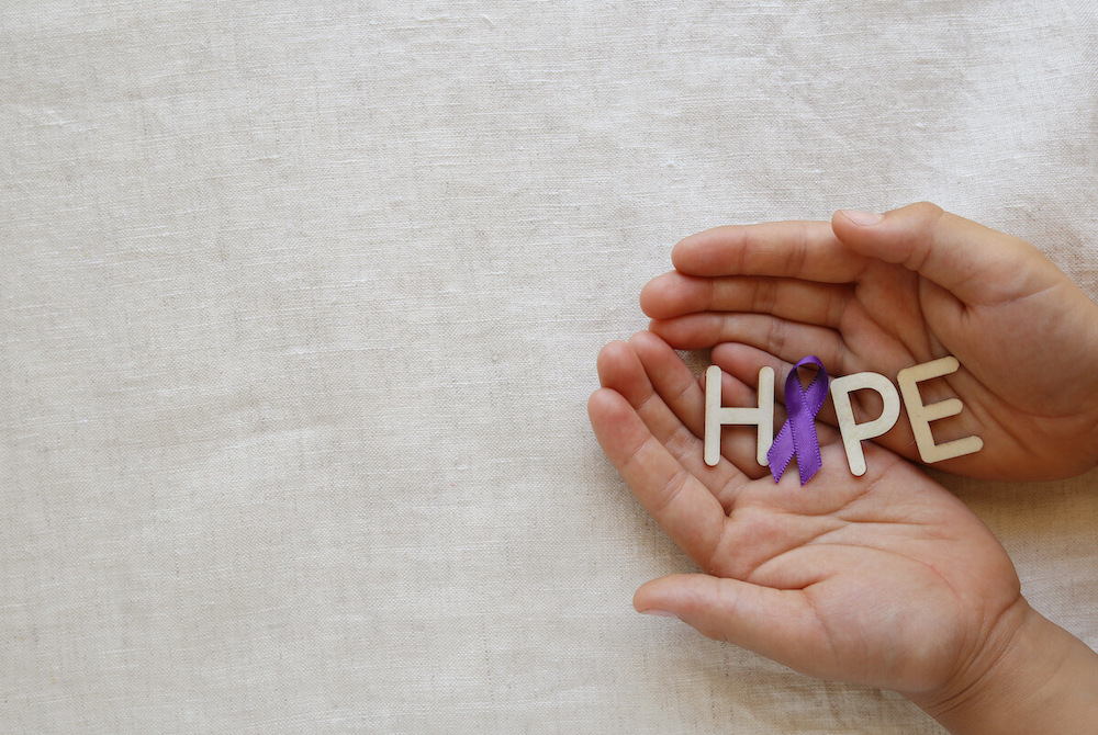 Pegasus Senior Living | Hands holding lettings spelling out hope, with a purper ribbon for the 