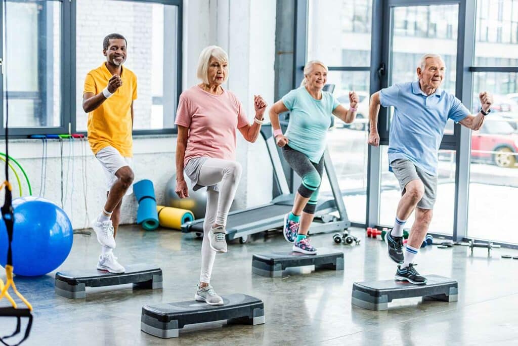 Broadway Mesa Village | happy multiethnic senior athletes synchronous exercising on step