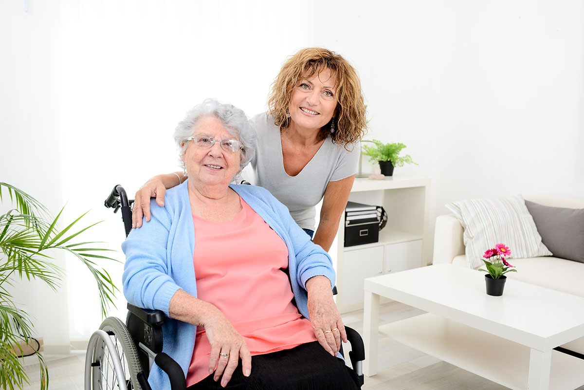Dunwoody Place | Cheerful woman visiting retirement home residence with elderly senior woman on wheelchair