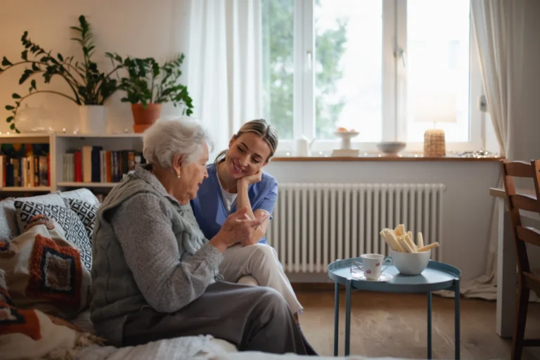 Senior woman and caregiver sitting on couch
