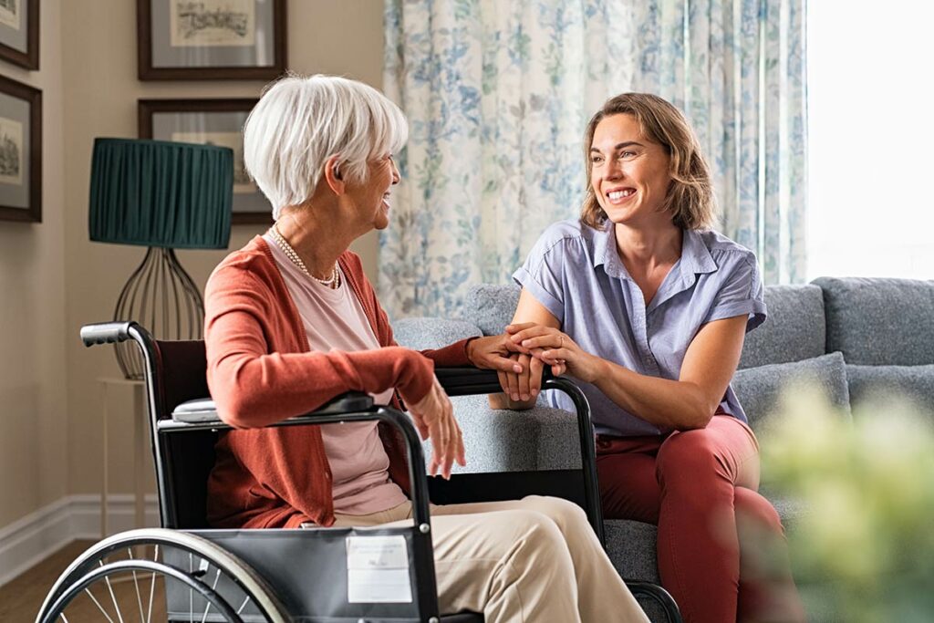 Gig Harbor Court | Senior woman in wheelchair smiling and talking with caregiver in living room