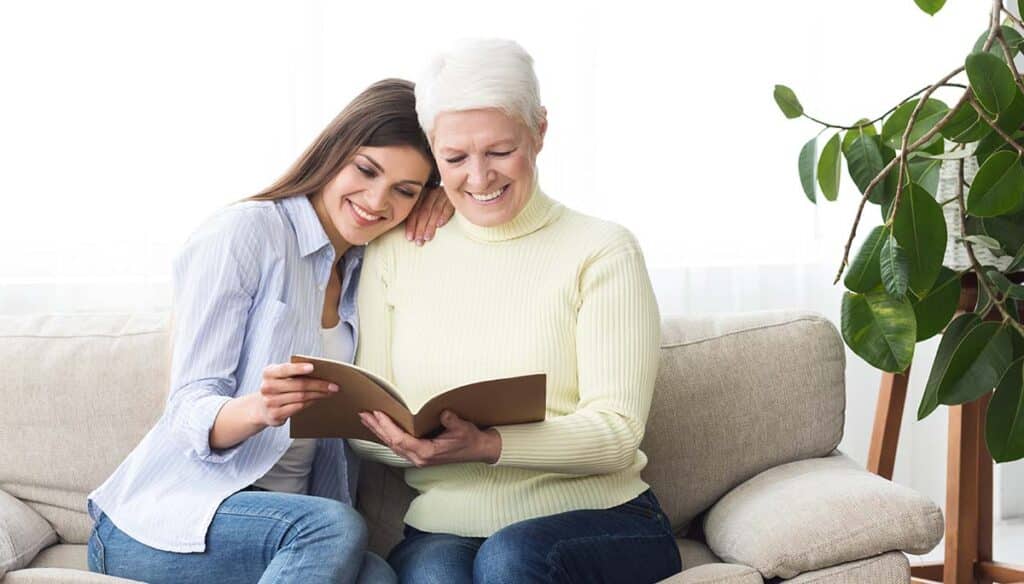 Glenwood Village of Overland Park | Senior woman smiling reading a book with her daughter
