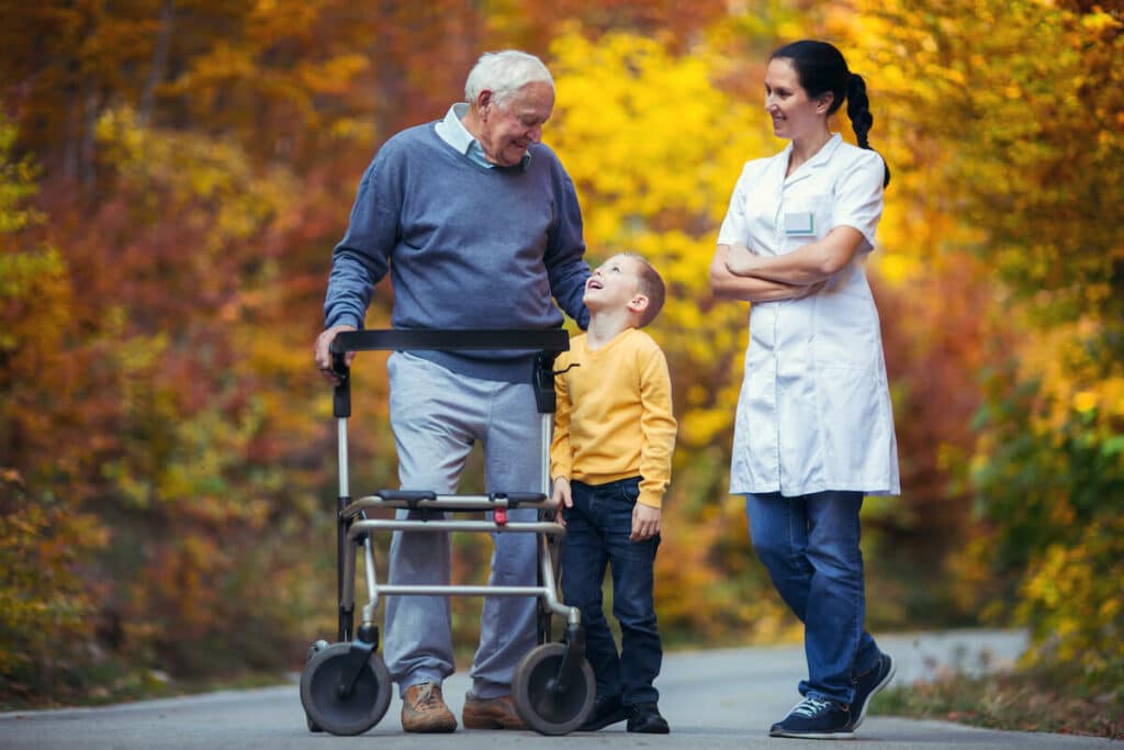 Glenwood Village of Overland Park | Senior man and his grandson walking outside with a caregiver