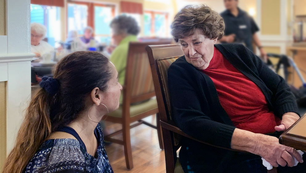 Greenhaven Place | Resident speaking with associate in dining room