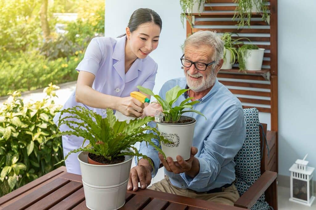 Historic Roswell Place | Happy senior man water plants with some help from his caregiver