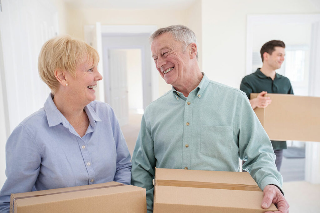 Laketown Village | Senior couple holding moving boxes and smiling