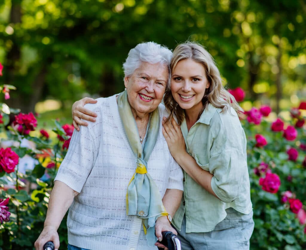 Magnolia Place of Roswell | Happy senior with caregiver outside with flowers