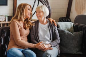 Magnolia Place of Roswell | Senior mother with adult daughter hugging each other on sofa in living room