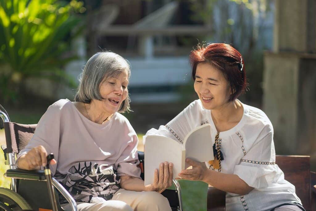 North Point Village | Senior woman with caregiver reading book outside