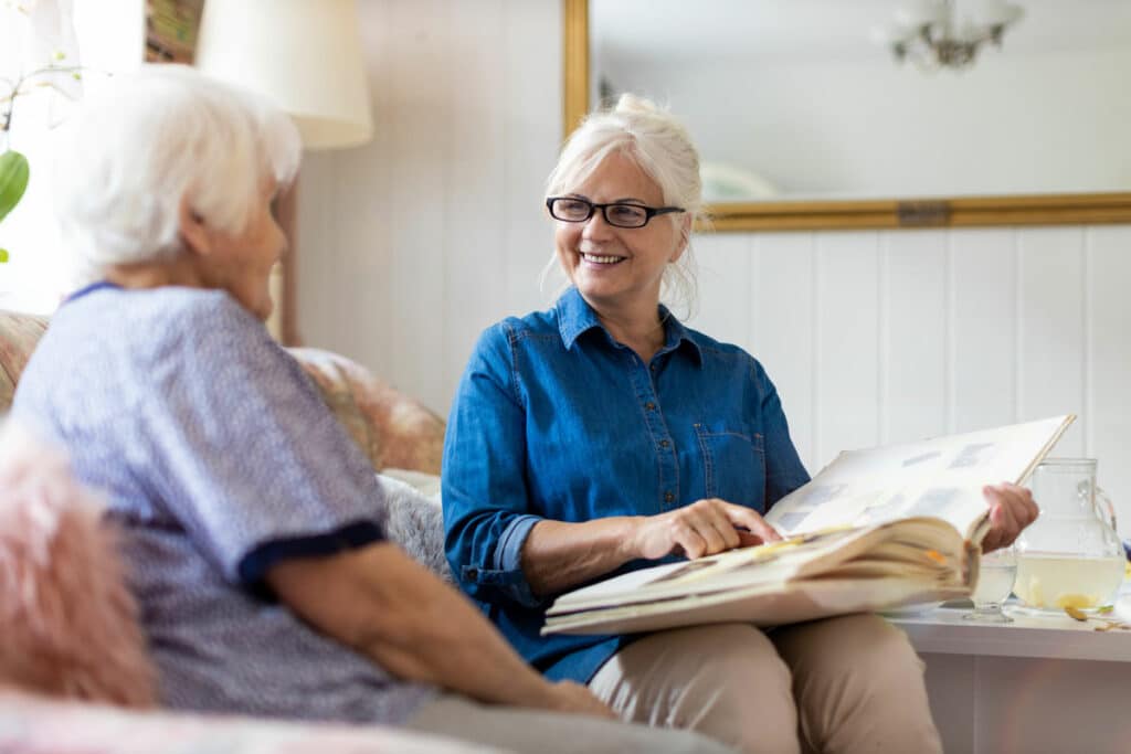 Pegasus Senior Living | Senior looking at photo album with memory care associate in apartment