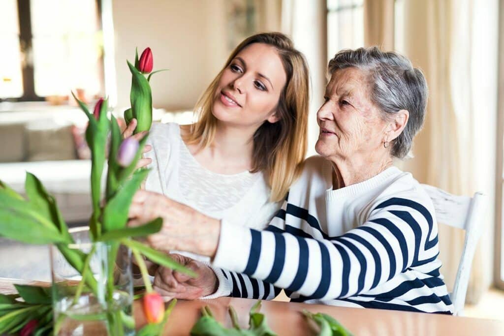Parmer Woods | Happy Senior woman with caregiver putting tulips in a vase