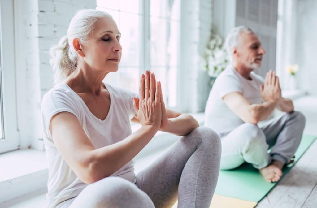 Pegasus Landing of Katy | 2 seniors with closed eyes practicing yoga and sitting on yoga mats