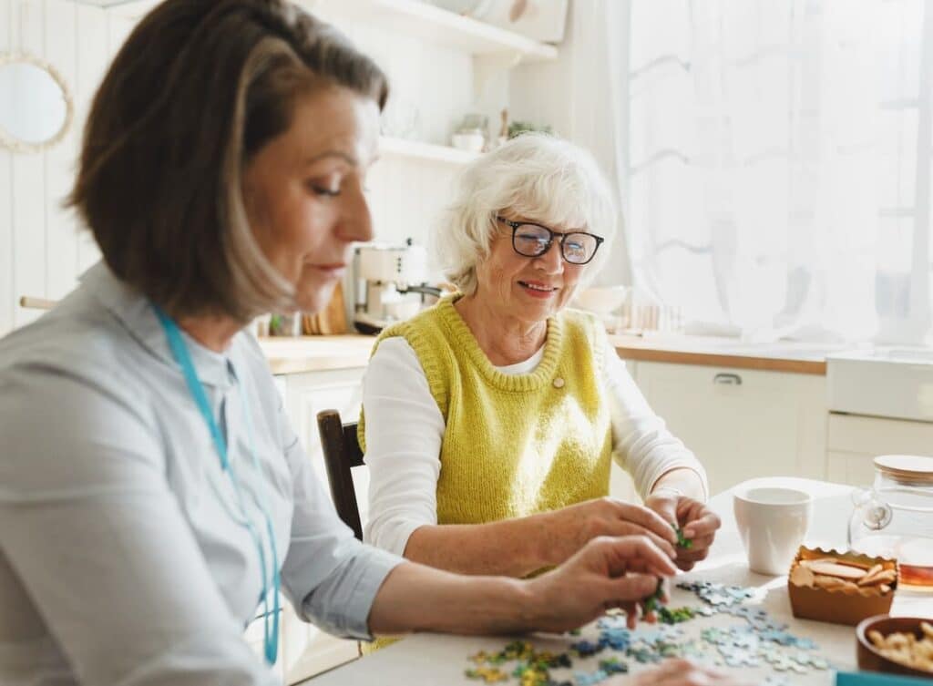 Team member and resident work on a jigsaw puzzle together