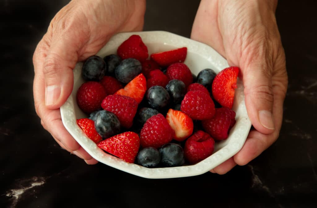 Pegasus Landing of South Plains | A senior woman's hands holding a bowl of blueberries and strawberries.