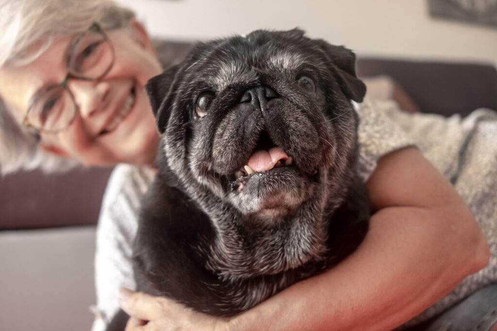 Pegasus Landing of South Plains | An elderly woman smiles with her arm around a black dog.