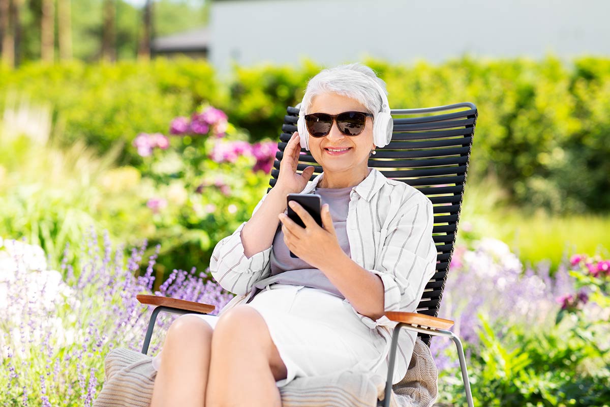 Ridgeland Place | Senior using smartphone and headphones in garden