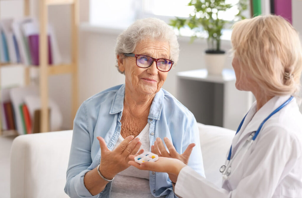 Pegasus Senior Living | Senior woman talking with her caregiver while taking her medication