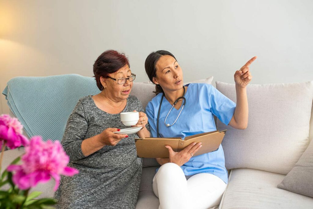Sterling Court at Roseville | Senior woman with caregiver on couch drinking tea
