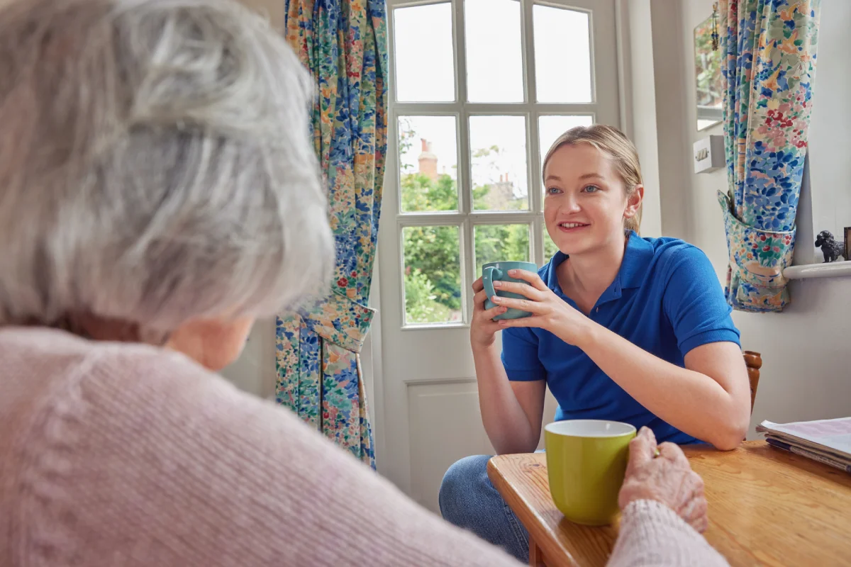 Senior woman chatting with team member over coffee