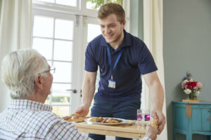 Pegasus Senior Living | Happy caregiver serving a senior breakfast