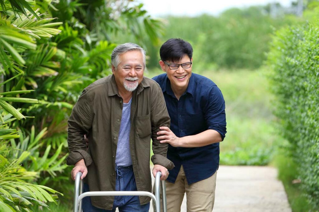 The Courtyards at Mountain View | Senior man using walker with the help of associate