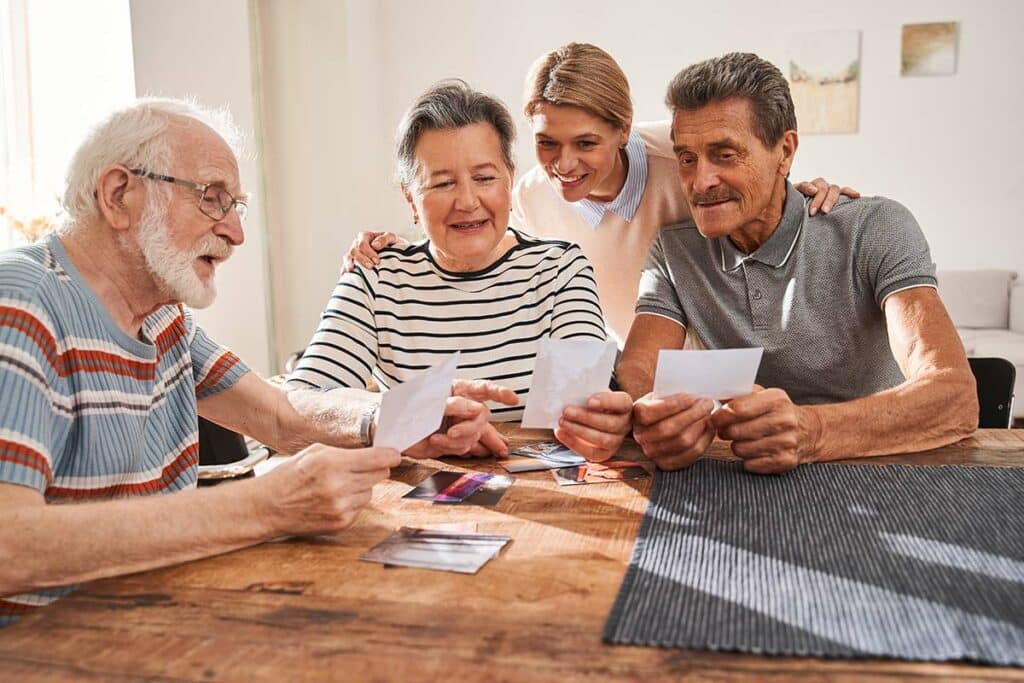 The Courtyards at Mountain View | Caregiver looking at photos with seniors