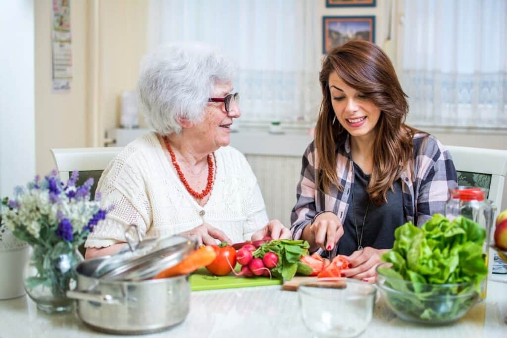Pegasus Senior Living | Senior woman with caregiver at table full of vegetables