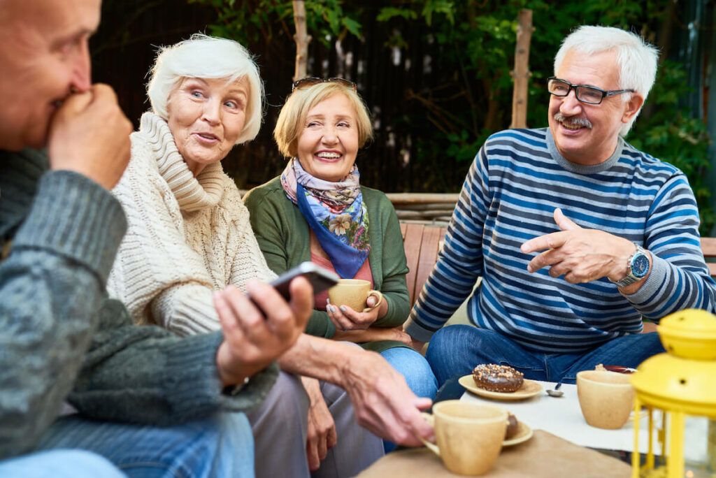 Pegasus Senior Living | Group of seniors gathered outside drinking coffee and eating donuts