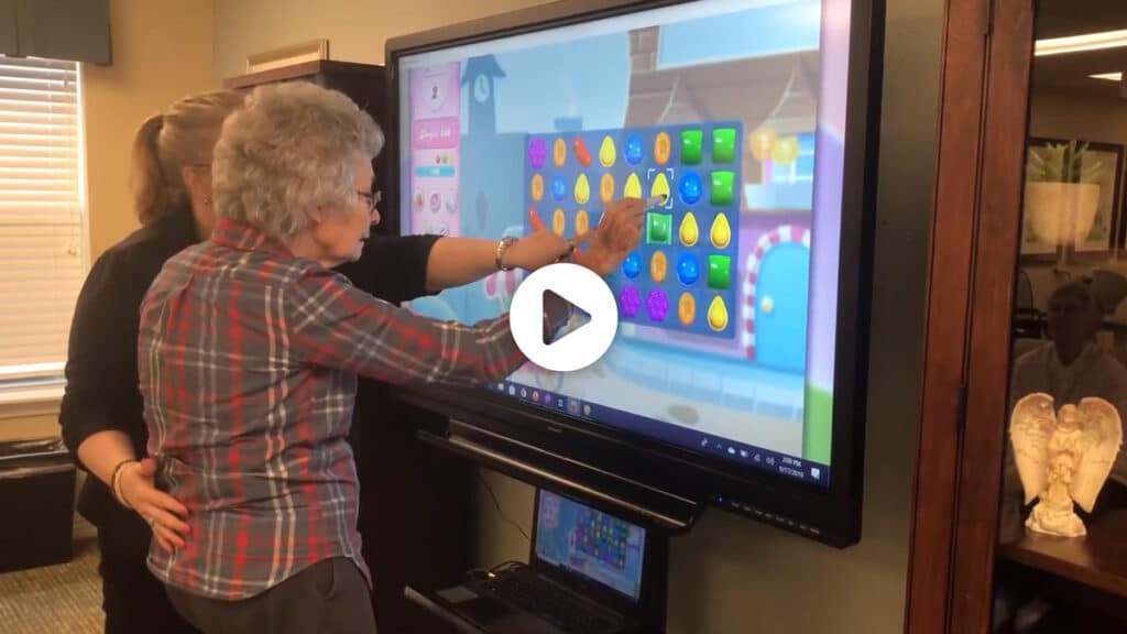 Pegasus Senior Living | Resident playing candy crush with associate