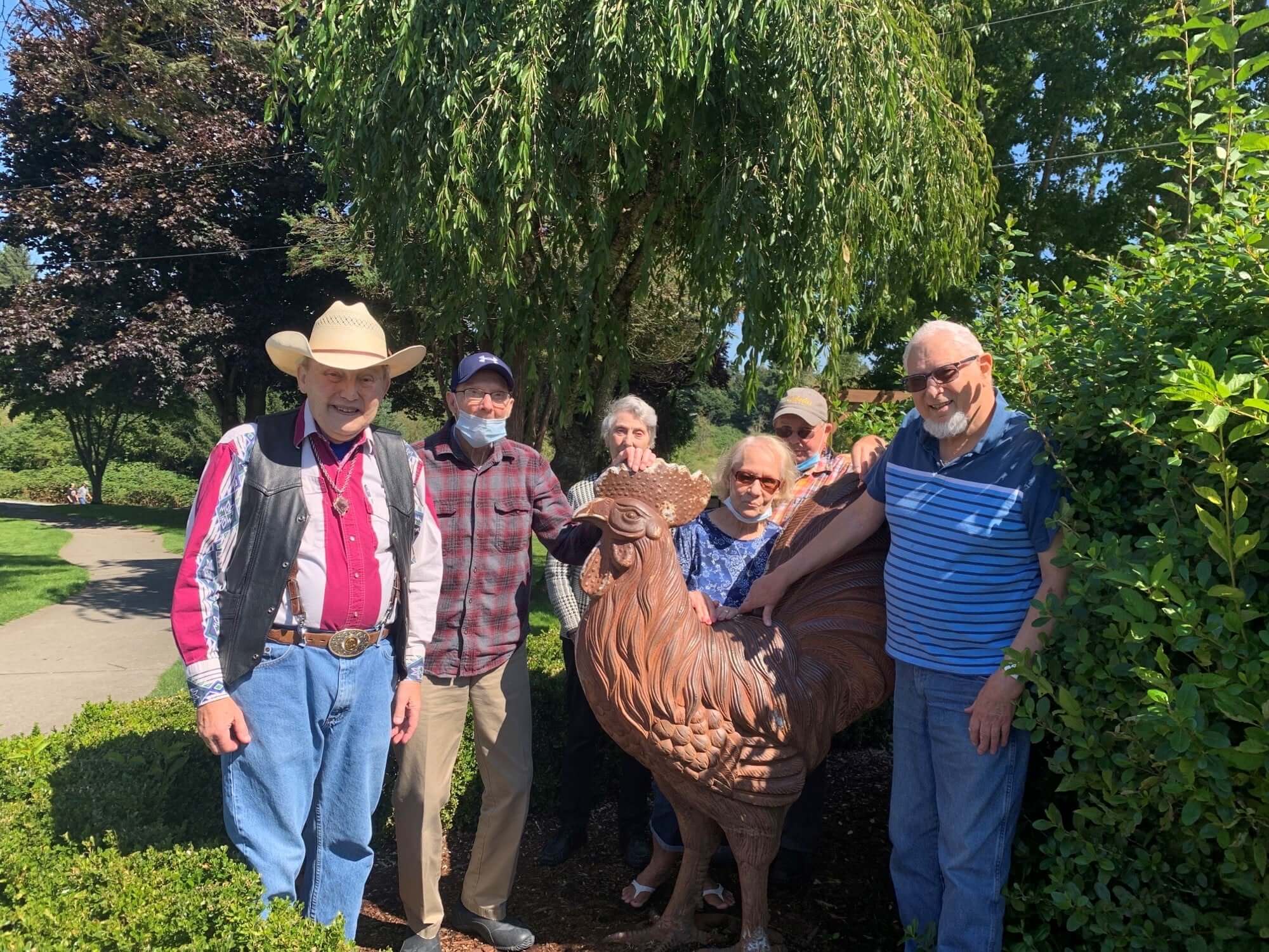 The Gardens at Marysville | Group of residents standing around a rooster statue