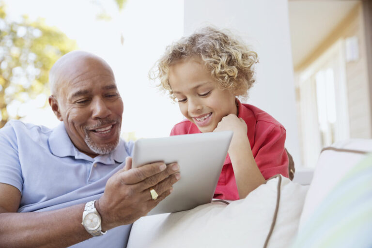 The Gardens at Marysville | Senior man and his grandkid looking at an ipad