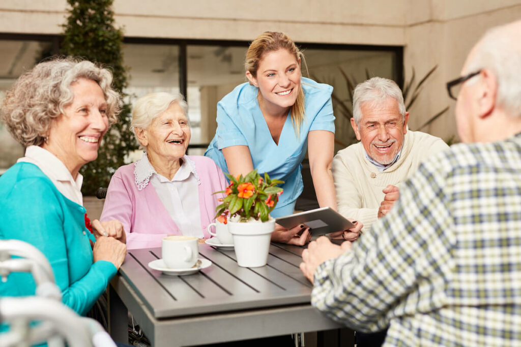 The Havens at Antelope Valley | Group of happy seniors and their caregiver talking at the table with coffee