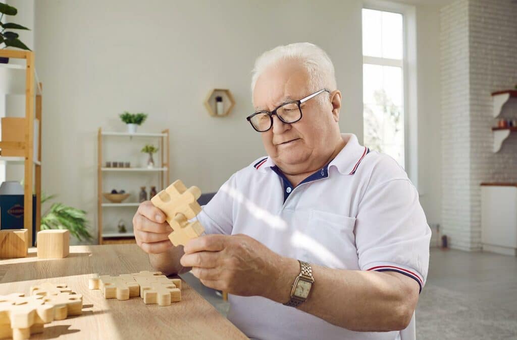 Pegasus Senior Living | Senior man using blocks shaped as puzzle pieces