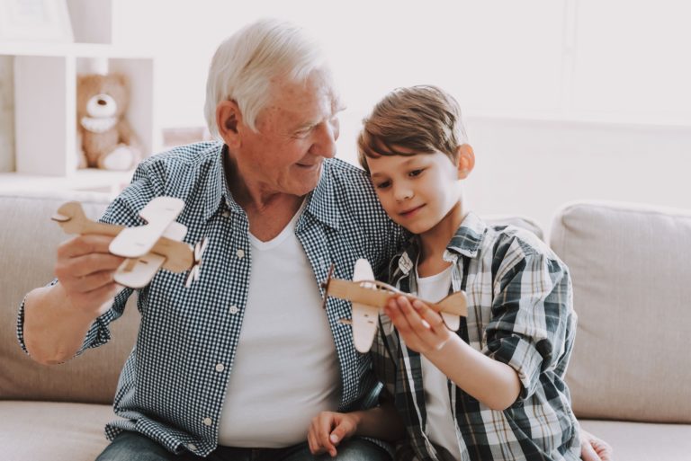 Town Village of Leawood | Senior man flying model planes with grandson