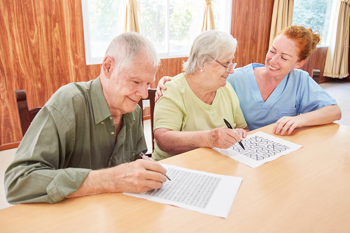 Tucson Place at Ventana Canyon | Caregiver helping senior couple with writing activity