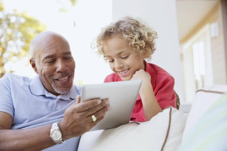 Whispering Winds of Apple Valley | Senior man using tablet with grandson