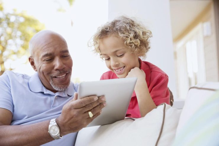 Whispering Winds of Apple Valley | Senior man using tablet with grandson