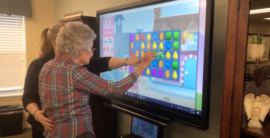 Pegasus Senior Living | Senior playing Candy Crush with associate on SmartBoard