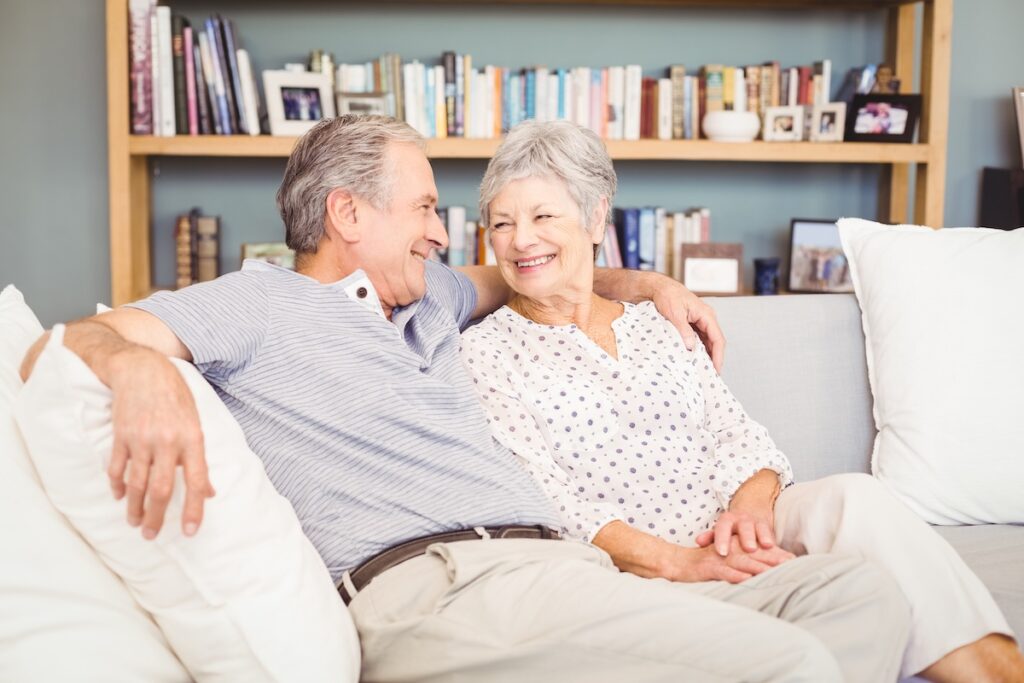 Pegasus Senior Living | Senior couple sitting on couch in front of a bookshelf