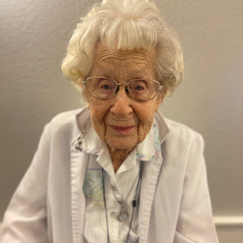 portrait of a senior woman with white hair and glasses smiling