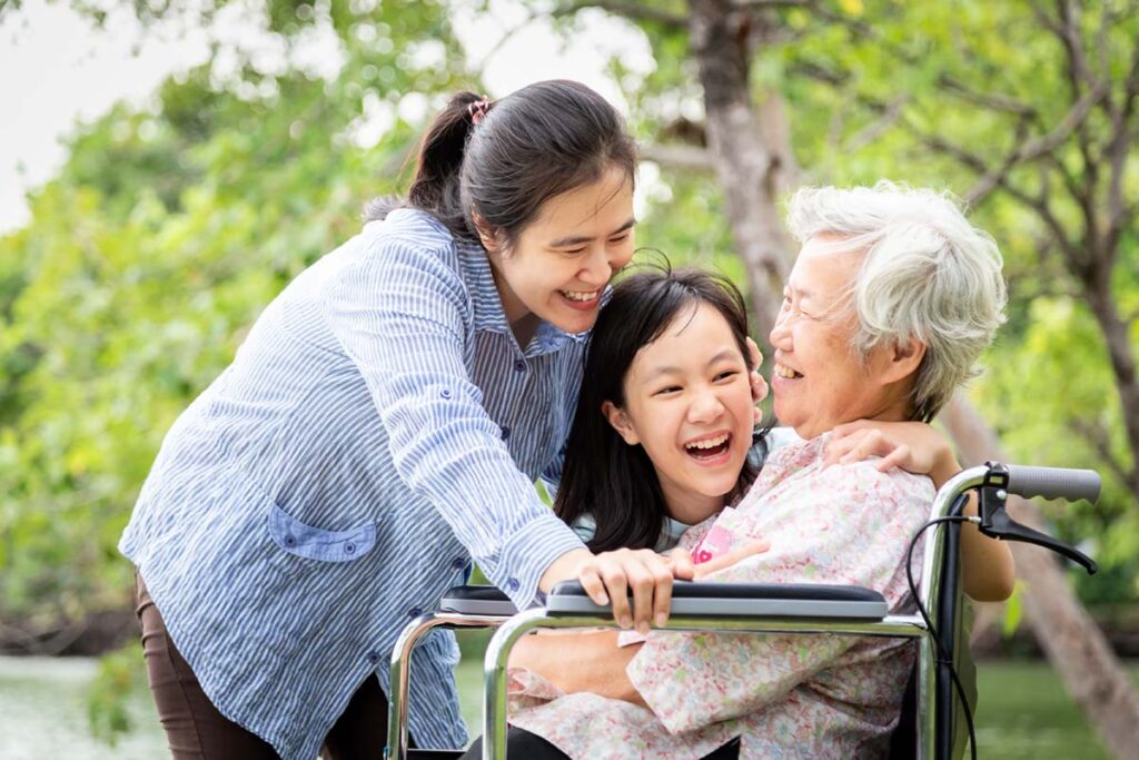 Parmer Woods at North Austin | Senior in wheelchair laughing with her daughter and granddaughter