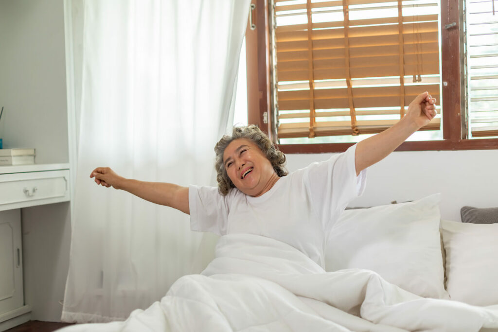 The Courtyards at Mountain View | Happy senior woman stretching after just waking up from sleeping