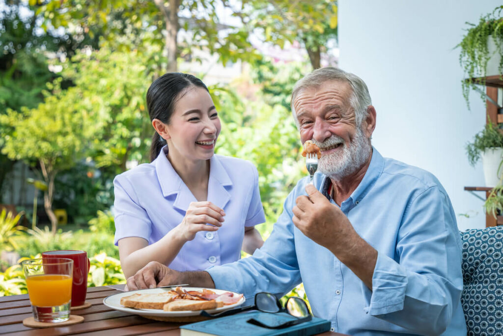 Tucson Place of Ventana Canyon | Senior man eating lunch while he sits with his caregiver