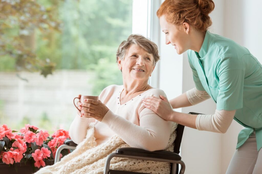 Gig Harbor Court | Happy senior woman drinking tea beside window with caregiver