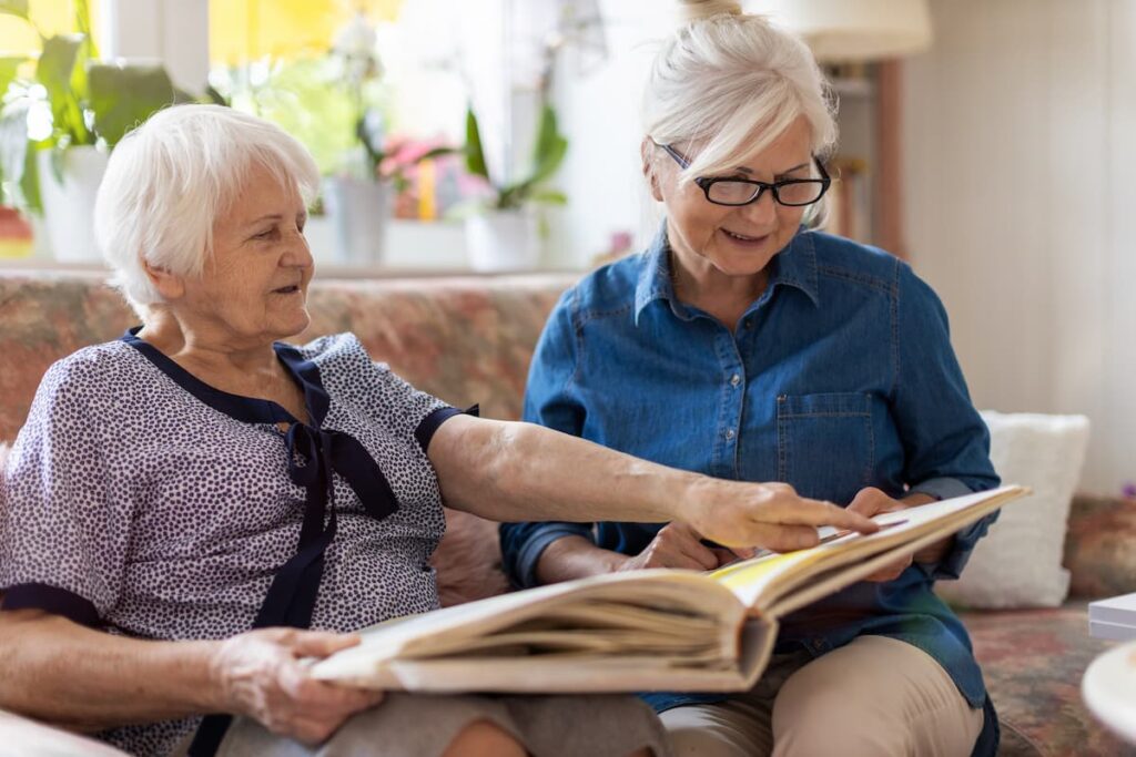 The Courtyards at Mountain View | Senior women looking at photo album while seated on couch